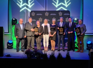 Władze samorządu województwa oraz nagrodzeni pozują do zdjęcia na scenie.